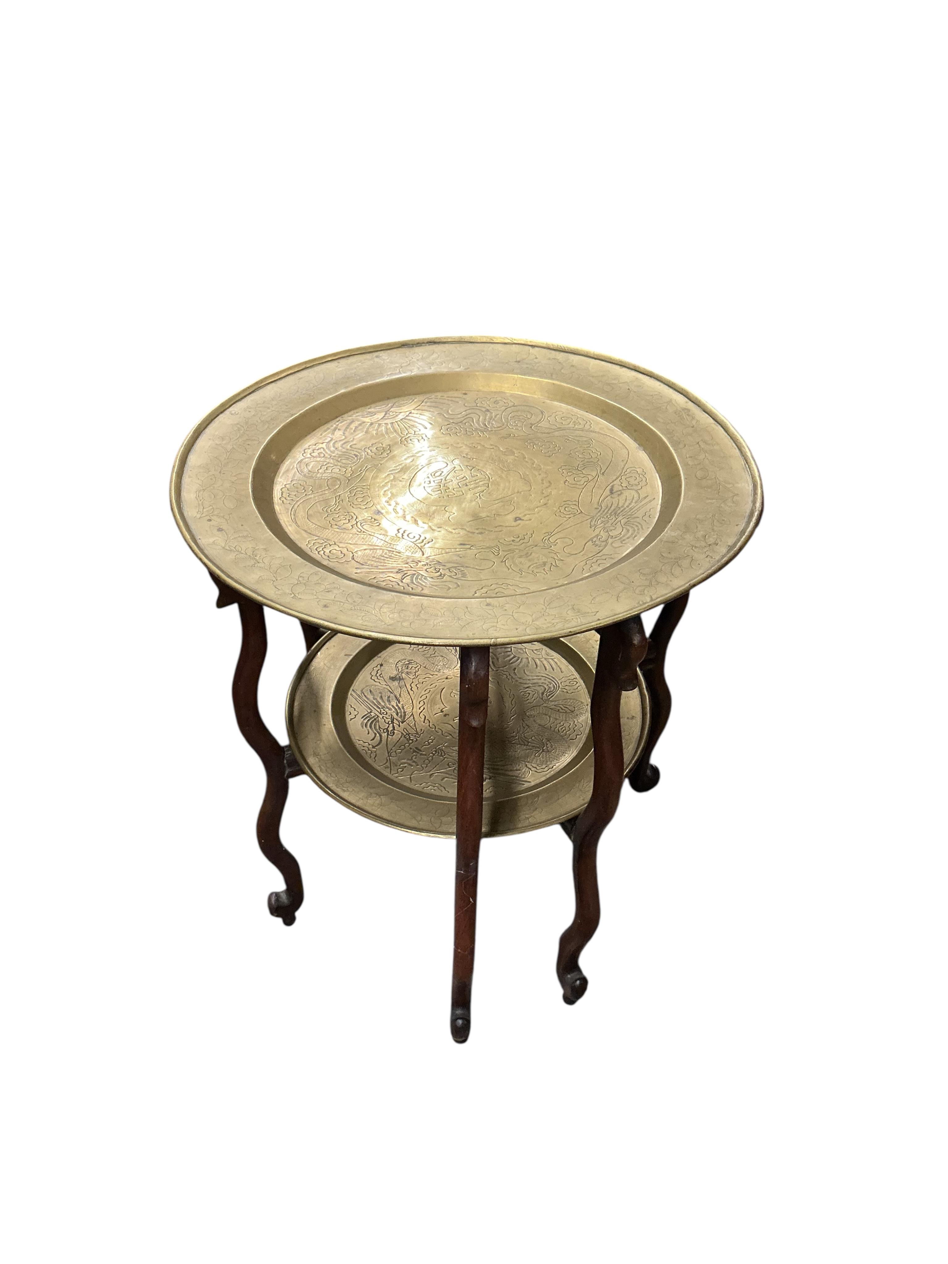 An early 20th century Chinese circular brass and hardwood two tier folding tea table, diameter 56cm, height 62cm